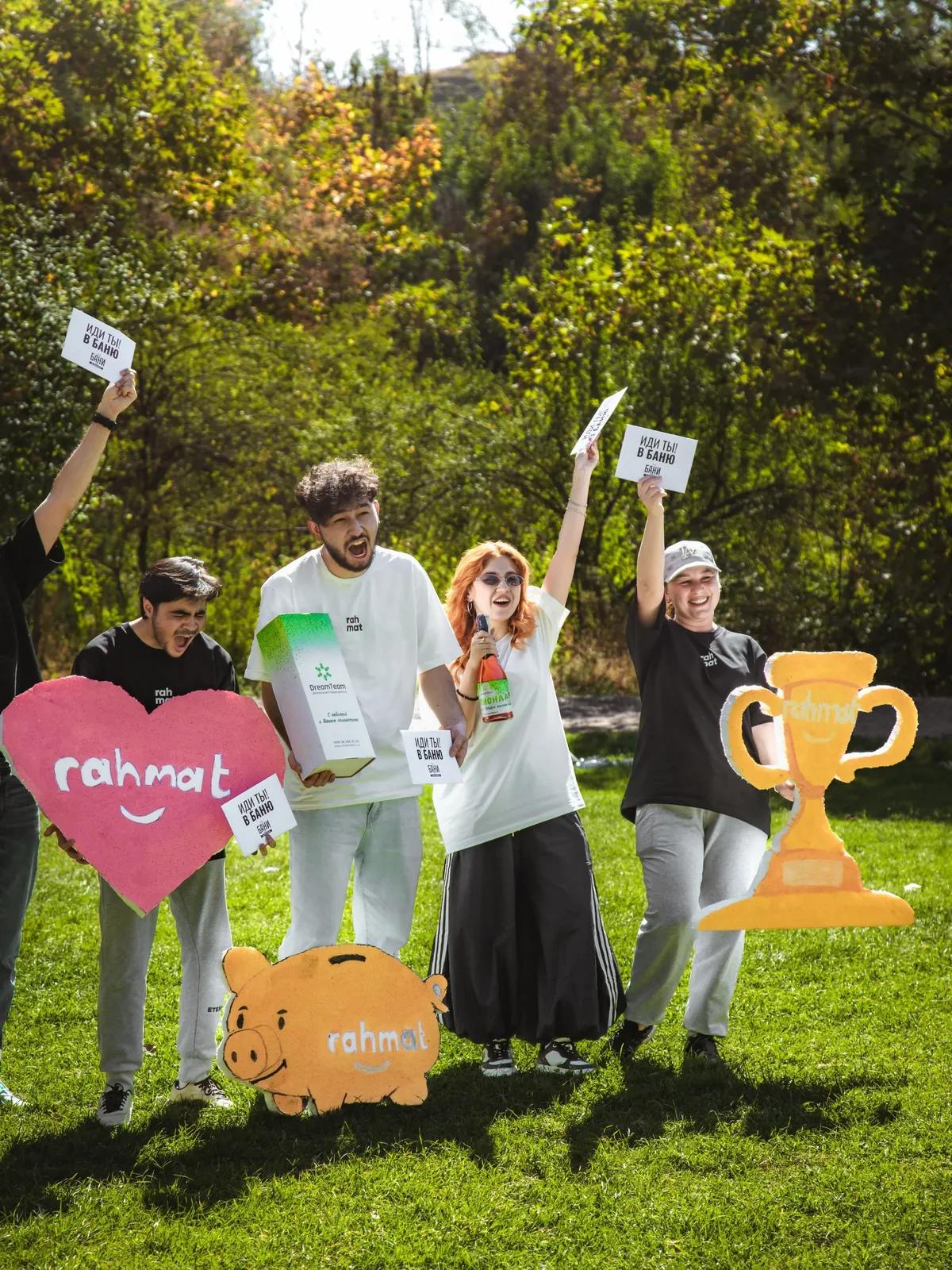 Rahmat employees in branded T-shirts on a lawn with signs and a cup