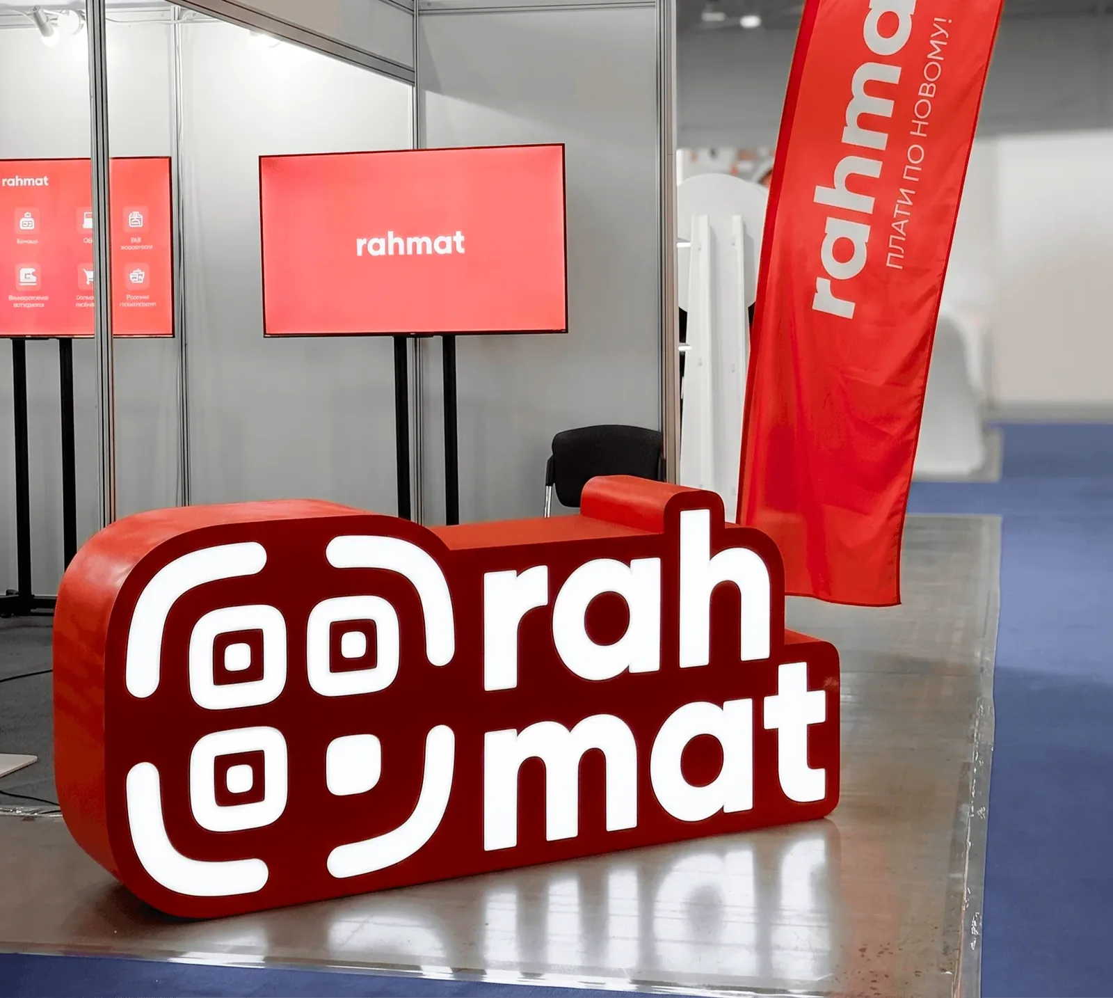 The Rahmat stand at an exhibition: a 3D logo, screens and a flag