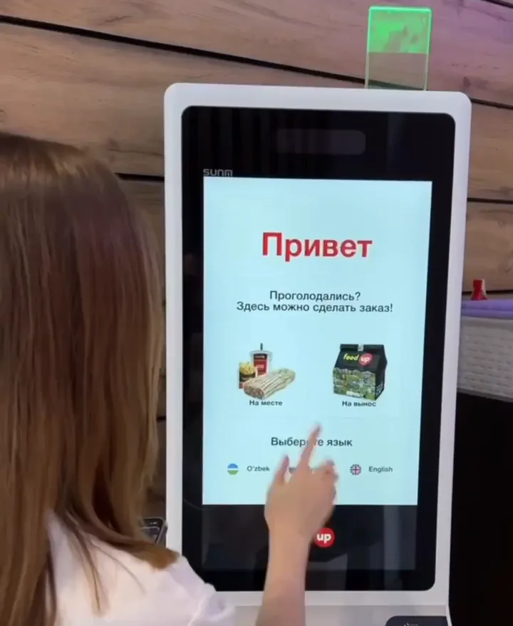 Mehmon Feed Up o‘z-o‘ziga xizmat kioskining salomlashuv ekranida tilni tanlamoqda